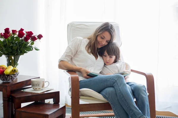 Madre, leggendo un libro al suo bambino, seduta sulla sedia a dondolo — Foto Stock