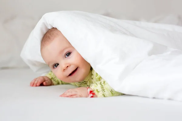Cute little six month old baby boy, playing under duvet at home — Stock Photo, Image