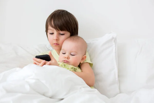 Little preschool boy laying in bed with his baby brother, playin — Stock Photo, Image