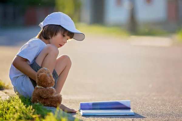 Красивый мальчик, читает книгу на улице, садится с — стоковое фото