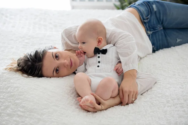 Mãe e seu filho bebê sorrindo e brincando em uma cama grande — Fotografia de Stock