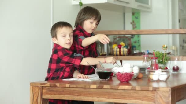 人の子供 男の子 イチゴを食べて自宅でイースターの卵を着色 — ストック動画