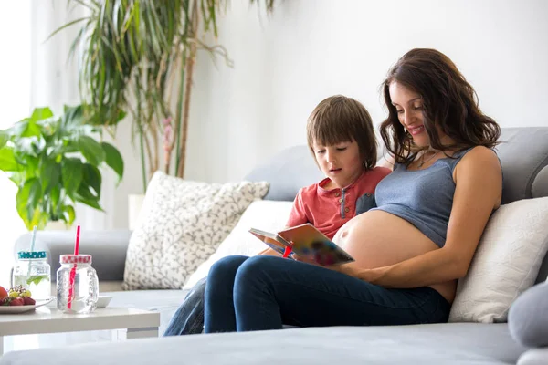 젊은 임신 여자, 그녀의 아들에 게 집에서 책을 읽고 — 스톡 사진