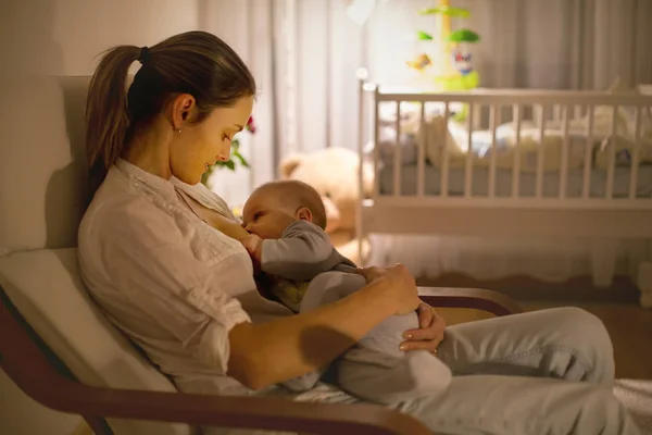 Young beautiful mother, breastfeeding her newborn baby boy at ni — Stock Photo, Image