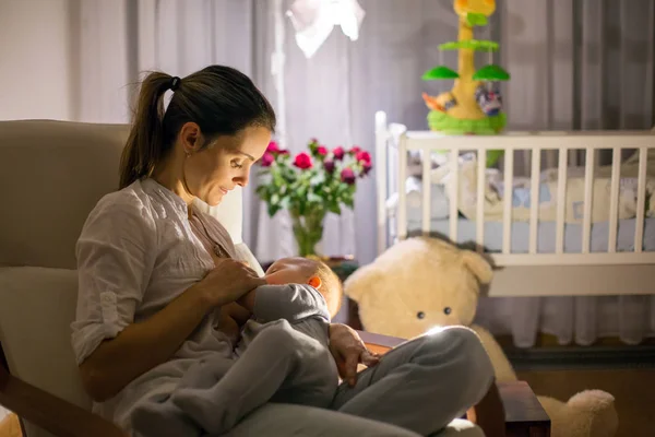 Jovem bela mãe, amamentando seu bebê recém-nascido menino em ni — Fotografia de Stock