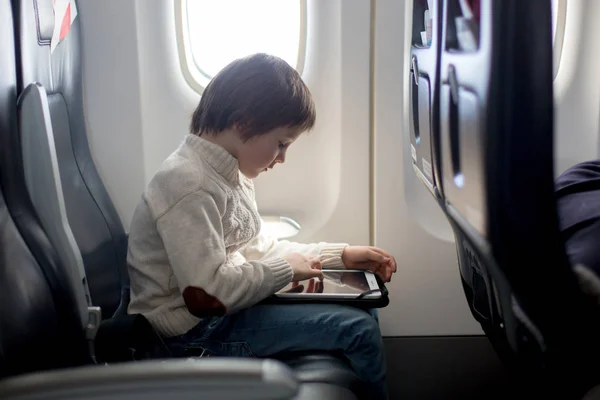 Schattig zes jaar oude jongen, spelen op tablen in vliegtuigen aan boord — Stockfoto