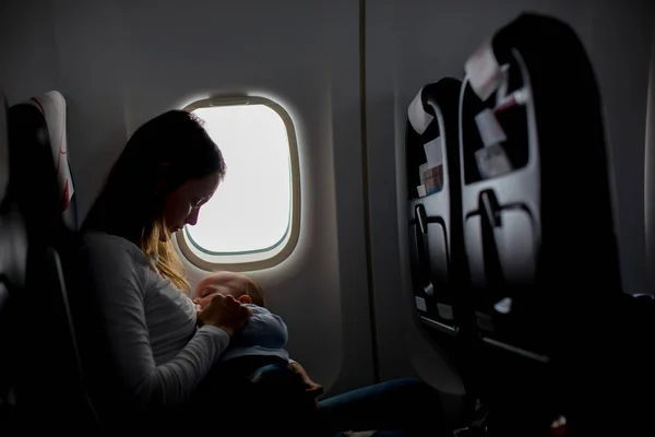 Молодая мама, играющая и кормящая грудью своего малыша на борту — стоковое фото
