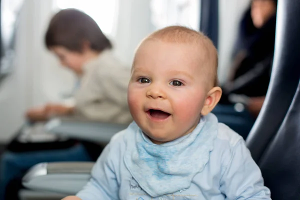 Söt baby pojke, leka med leksaker ombord på flygplan, resor — Stockfoto