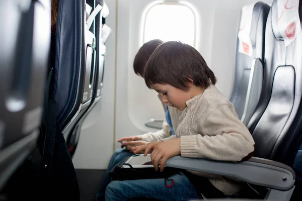 Söt förskola barn, titta genom fönstret i flygplan — Stockfoto