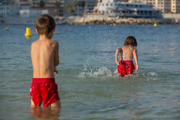 Dos niños dulces, salpicándose entre sí con agua en la playa — Foto de Stock