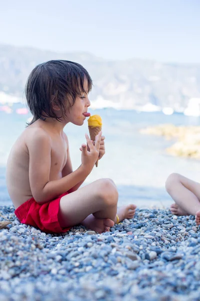 两个快乐的孩子，男孩兄弟，在海滩上吃冰淇淋 — 图库照片