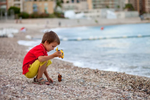 Ragazzo, giocare sulla spiaggia la sera dopo la pioggia con i giocattoli — Foto Stock