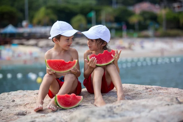 Dos niños pequeños, hermanos varones, comiendo sandía en la playa — Foto de Stock