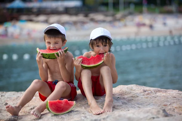 Dos niños pequeños, hermanos varones, comiendo sandía en la playa — Foto de Stock