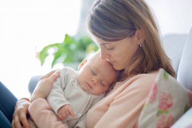 Genç anne, yeni doğmuş bebeğini şefkatle kucaklıyor.