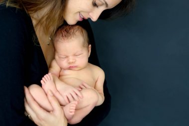 Öpüşme ve yeni doğan oğlu gri arka plan, tende sarılma anne