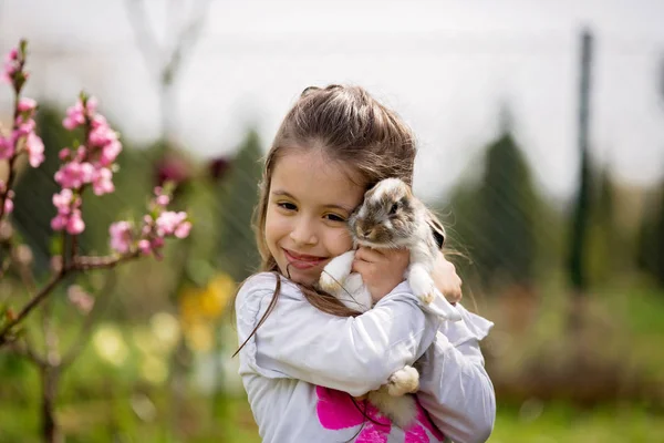 Niña jugando con conejo blanco en el parque en un verano soleado —  Fotos de Stock