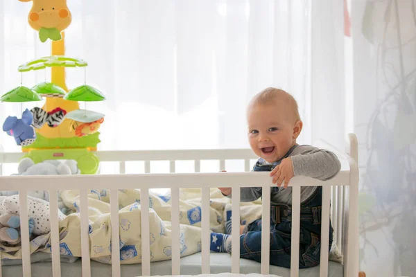 Ler barn pojke, leker med lilla kanin leksak i babysäng — Stockfoto