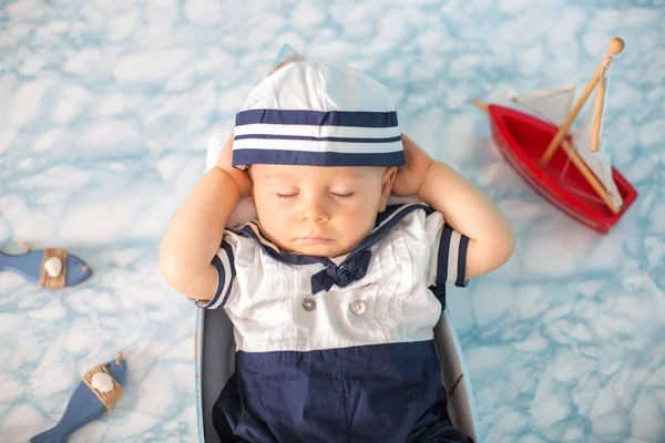 Cute toddler baby boy sleeping in wooden boat with fishes, starf — Stock Photo, Image