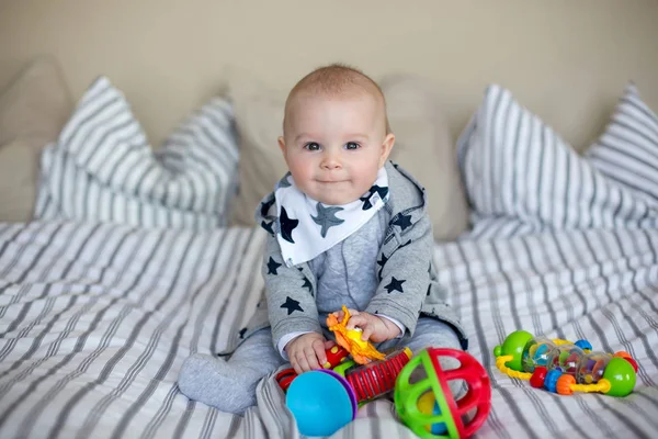 Lindo bebé, jugando en casa en la cama con un montón de colorf — Foto de Stock