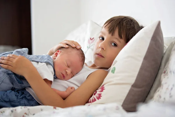 Mooie jongen, knuffelen met tederheid en zorg zijn pasgeboren baby — Stockfoto