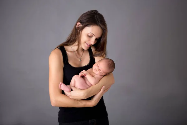 母にキスをし優しくて灰色の背景で生まれたばかりの息子を抱いて — ストック写真