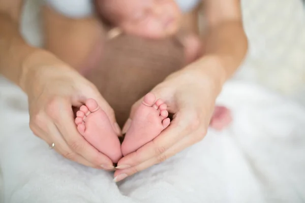 Pequeño bebé pies en madres manos — Foto de Stock