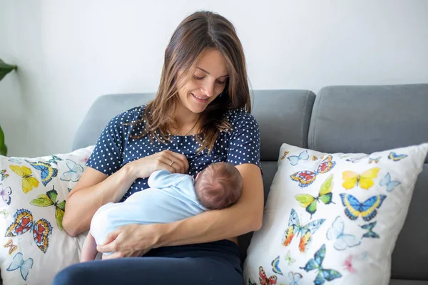 若い母親は、彼女の生まれたばかりの赤ちゃんの男の子を母乳で育てる — ストック写真