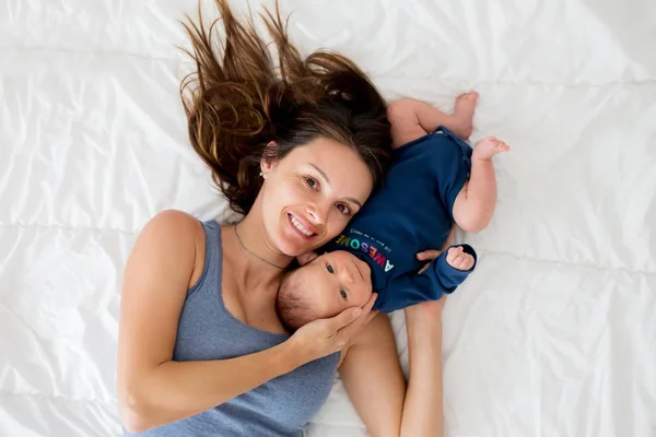 Mãe e bebê menino, deitado na cama, abraçando com amor — Fotografia de Stock