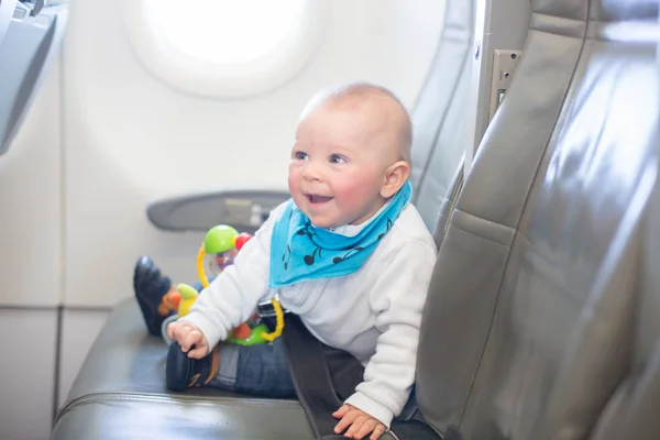 Söt liten pojke, leka med leksaker ombord på flygplan — Stockfoto