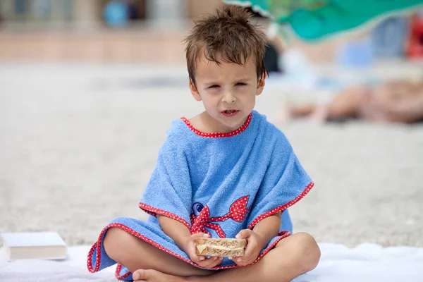 Netter Junge, der am Strand Sandwich isst — Stockfoto