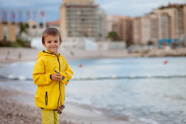 少年は、おもちゃで雨の後の夕方の浜辺で遊んで — ストック写真