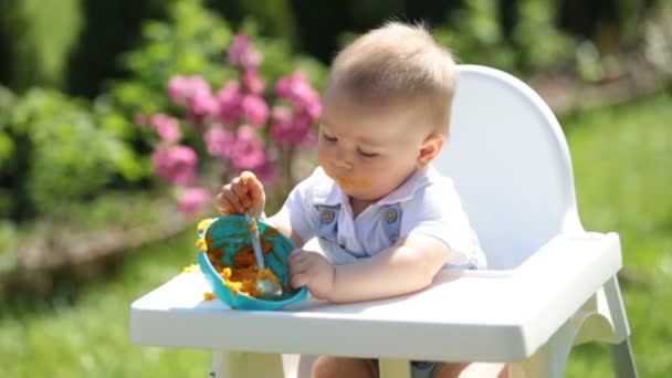 Lindo Niño Con Cara Desordenada Comiendo Almuerzo Jardín Sentado Silla — Vídeos de Stock