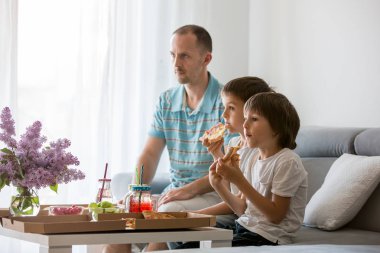 Baba ve onun iki erkek, çocuk, evde pizza yiyip watc