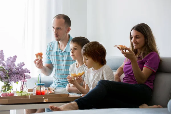 Mooie jonge gezin met kinderen, eten pizza thuis en w — Stockfoto