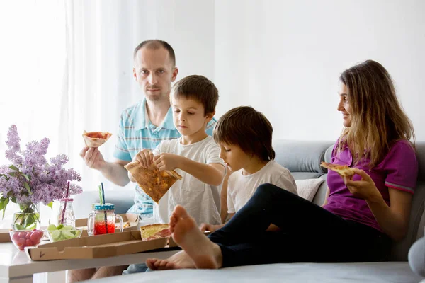 Piękne młode rodziny z dziećmi, jedzenie pizzy w domu i w — Zdjęcie stockowe