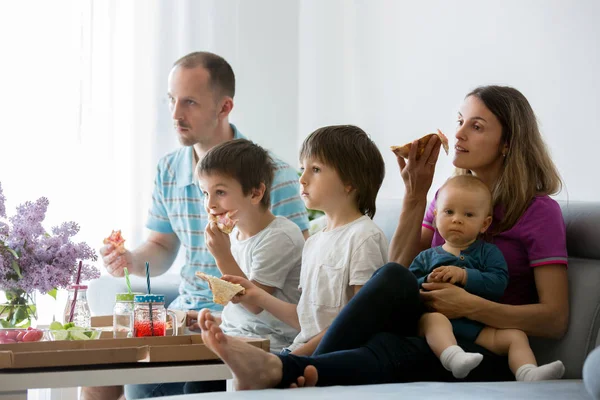 Mooie jonge gezin met drie kinderen, eten pizza thuis — Stockfoto