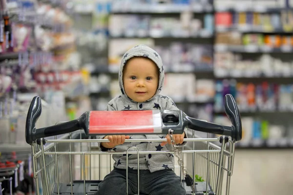 Menino bebê, sentado em um carrinho de compras na mercearia, s — Fotografia de Stock