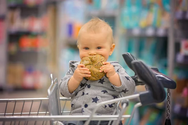 Tipegő baba fiú ül a kosárban, élelmiszerbolt, s — Stock Fotó