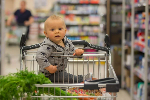 Menino bebê, sentado em um carrinho de compras na mercearia, s — Fotografia de Stock