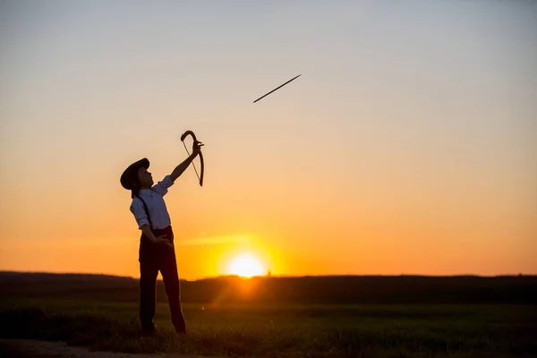 Silueta de niño jugando con arco y flechas, brotes de tiro con arco —  Fotos de Stock