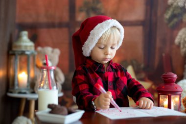 Tatlı sarışın çocuk, Noel Baba 'ya mektup yazıyor.