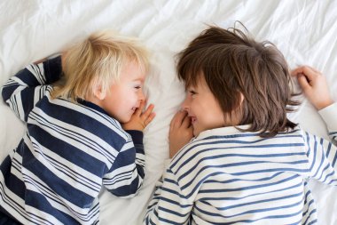 Kardeşler, evde oynuyorlar, ayaklarını gıdıklayıp gülüyorlar. 