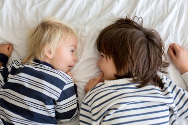 Kardeşler, evde oynuyorlar, ayaklarını gıdıklayıp gülüyorlar. 