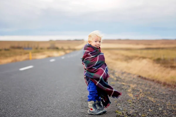 Criança bonita, de pé em uma estrada em um dia muito ventoso, envolto — Fotografia de Stock