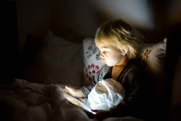 Happy peuter jongen kijken nachten verhaal 's nachts op tablet — Stockfoto