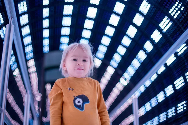 Kleiner kleiner Junge in einem Raumschiff, beleuchtet in verschiedenen Farben — Stockfoto
