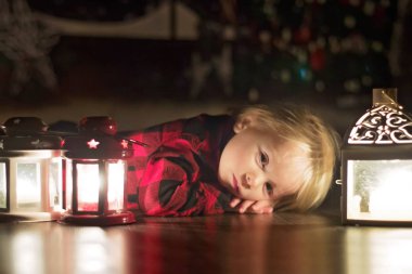 Tatlı çocuk evde yerde mumlarla yatıyor, bekliyor.