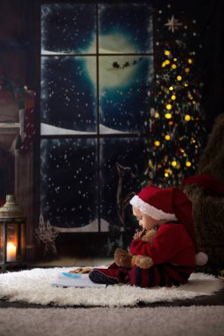 Tatlı çocuk, Noel gecesi evde kitap okuyor.