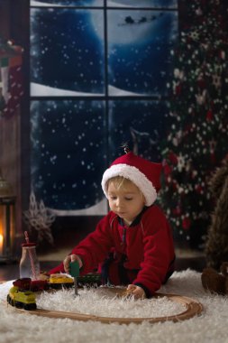 Tatlı çocuk, gece vakti evdeki ahşap trenle oynuyorsun. 